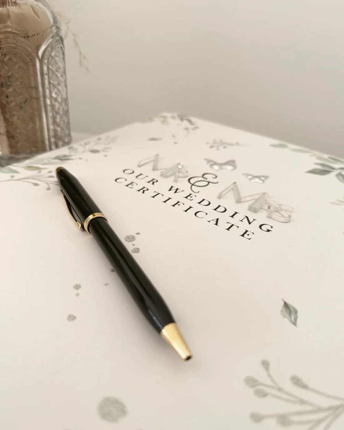 A wedding certificate folder with a gold pen